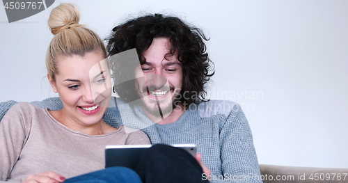Image of couple relaxing at  home with tablet computers