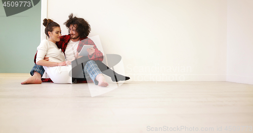 Image of Young Couple using digital tablet on the floor