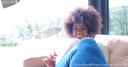 Image of african american woman at home using digital tablet