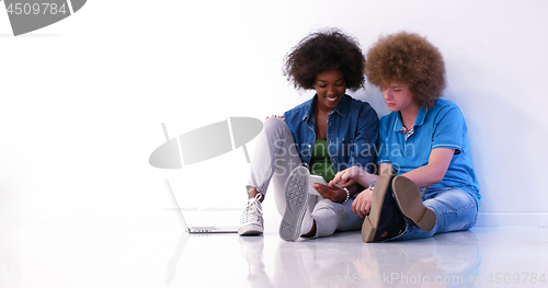 Image of multiethnic couple sitting on the floor using a laptop and table
