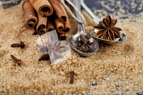 Image of Brown cane sugar, cinnamon sticks and star anise closeup on blac