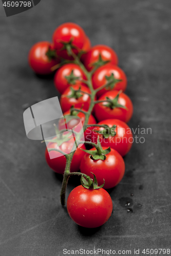 Image of Fresh organic cherry tomatoes bunch closeup on black board.