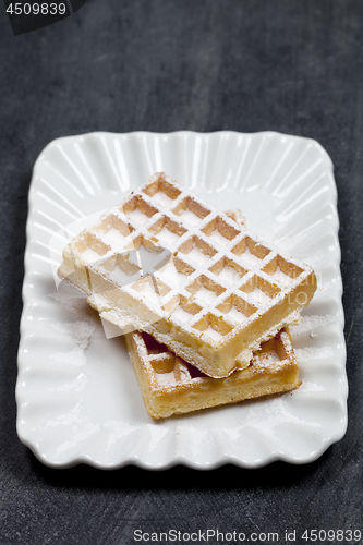 Image of Belgium waffers with sugar powder on ceramic plateon black board