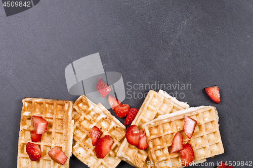 Image of Belgium waffers and strawberries on black board background. 