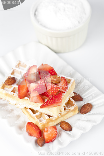 Image of Belgium waffers with sugar powder, strawberries and almonds on c