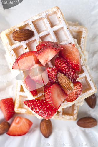 Image of Belgium waffers with sugar powder, strawberries, almonds and cho