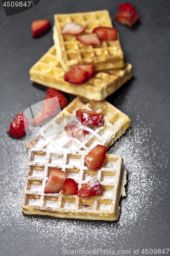 Image of Belgium waffers with strawberries and sugar powder on black boar