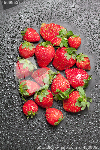 Image of Fresh ripe strawberry with water drops on black background.