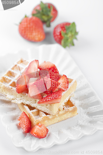 Image of Belgium waffers with sugar powder and strawberries on ceramic pl