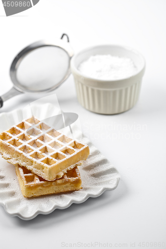 Image of Belgium waffers with sugar powder on ceramic plate and strainer 