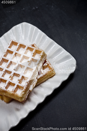 Image of Belgium waffers with sugar powder on ceramic plateon black board