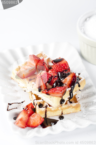 Image of Belgium waffers with sugar powder, strawberries and chocolate on