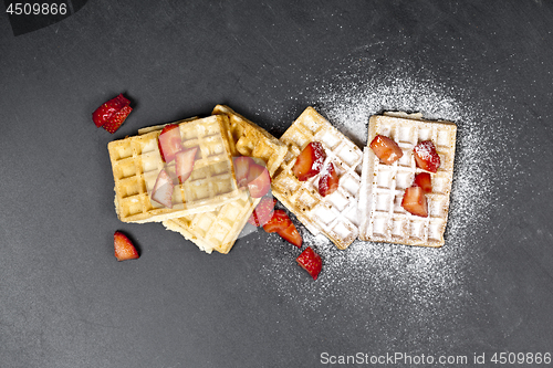 Image of Belgium waffers with strawberries and sugar powder on black boar