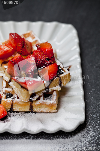 Image of Belgium waffers with sugar powder, strawberries and chocolate on