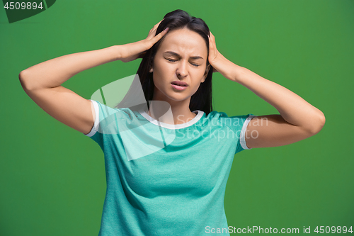 Image of Woman having headache. Isolated over green background.