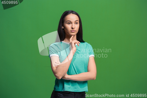 Image of Let me think. Doubtful pensive woman with thoughtful expression making choice against grreen background