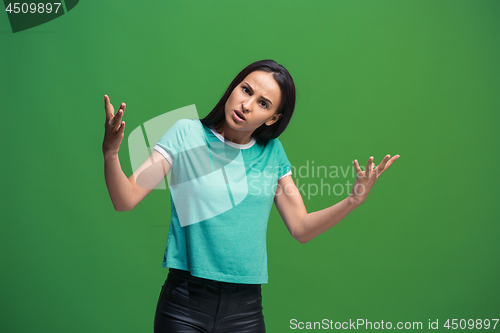 Image of Beautiful female half-length portrait isolated on green studio backgroud. The young emotional surprised woman