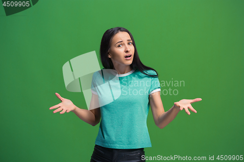 Image of Beautiful female half-length portrait isolated on green studio backgroud. The young emotional surprised woman