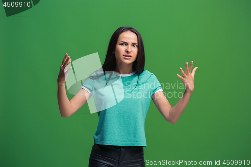 Image of Beautiful female half-length portrait isolated on green studio backgroud. The young emotional surprised woman