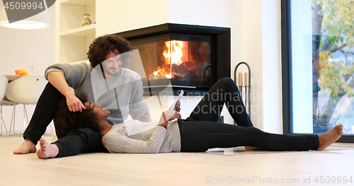 Image of multiethnic couple using tablet computer on the floor
