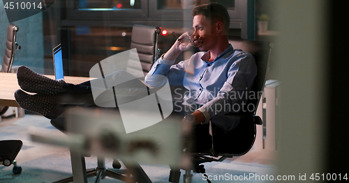 Image of businessman sitting with legs on desk at office