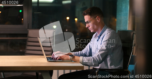 Image of man working on laptop in dark office