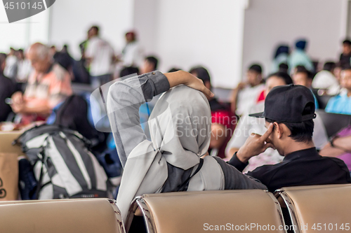 Image of Modern muslim islamic asian couple sitting and waiting for flight departure at international airport terminal