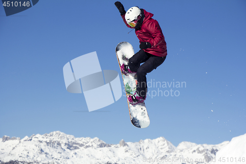 Image of Snowboarder jumping through air with blue sky in background