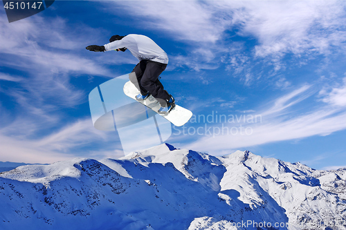 Image of Snowboarder jumping through air with blue sky in background