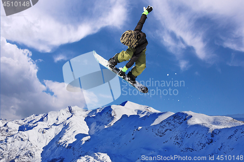 Image of Snowboarder jumping through air with blue sky in background