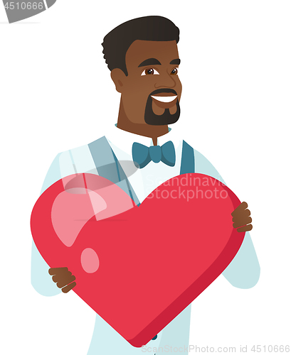 Image of Young african-american groom holding a big heart.