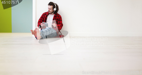 Image of young man listenig music on tablet at home