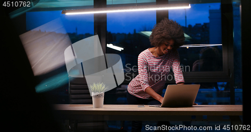 Image of black businesswoman using a laptop in night startup office