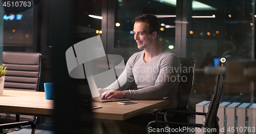 Image of man working on laptop in dark office