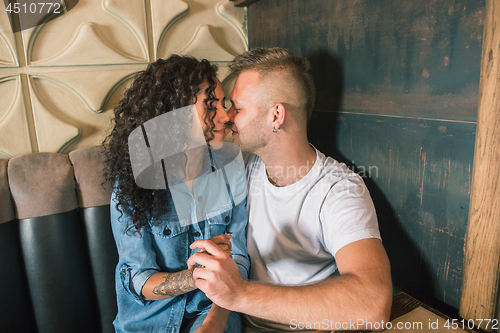 Image of Happy young couple is drinking coffee and smiling while sitting at the cafe