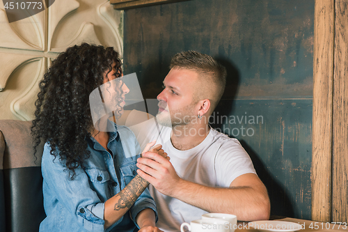 Image of Happy young couple is drinking coffee and smiling while sitting at the cafe