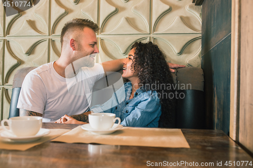 Image of Happy young couple is drinking coffee and smiling while sitting at the cafe