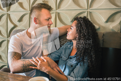 Image of Happy young couple is drinking coffee and smiling while sitting at the cafe