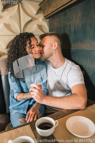 Image of Happy young couple is drinking coffee and smiling while sitting at the cafe