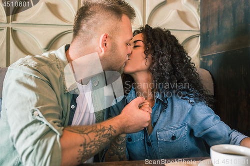 Image of Happy young couple is drinking coffee and smiling while sitting at the cafe