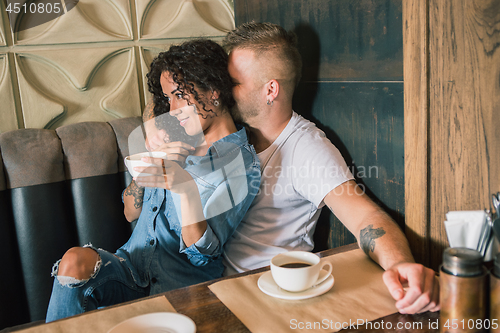 Image of Happy young couple is drinking coffee and smiling while sitting at the cafe