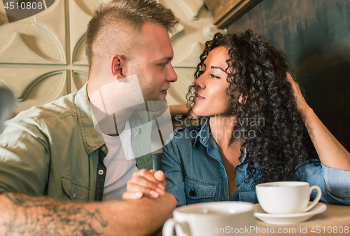 Image of Happy young couple is drinking coffee and smiling while sitting at the cafe