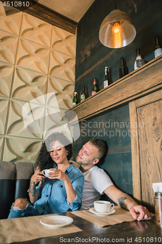 Image of Happy young couple is drinking coffee and smiling while sitting at the cafe