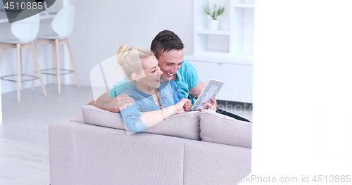 Image of couple relaxing at  home with tablet computers