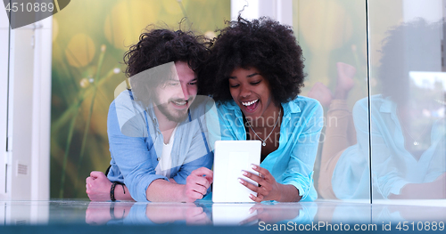 Image of Couple relaxing together at home with tablet computer