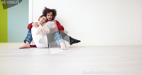 Image of Young Couple using digital tablet on the floor