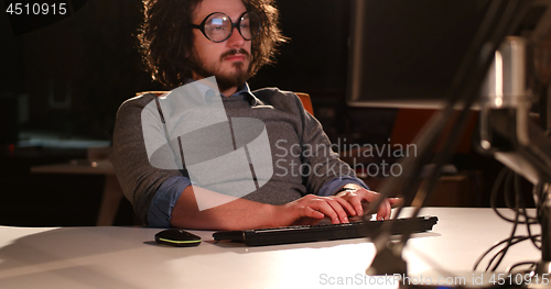 Image of man working on computer in dark office