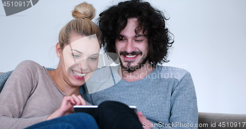 Image of couple relaxing at  home with tablet computers