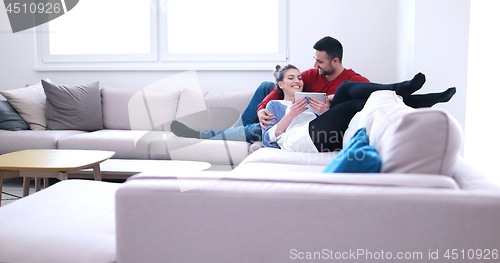 Image of couple relaxing at  home with tablet computers