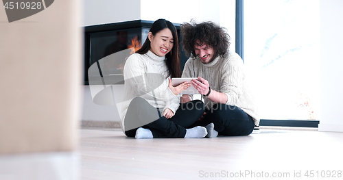 Image of Young Couple using digital tablet on the floor